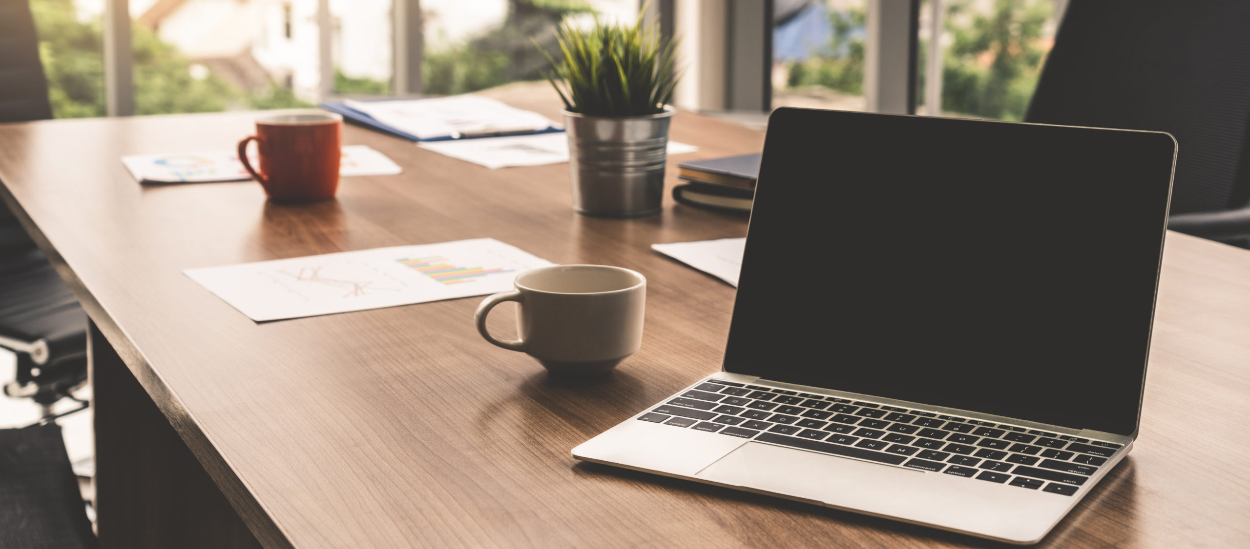 Laptop computer with opened lid on table in meeting room of office workspace.